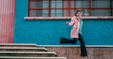 Full Length Of Woman In Mid-Air Jumping Over Steps By House