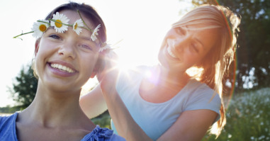 Mother tying daisy chain around daughter’s head