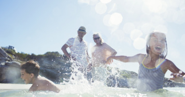 Family splashing each other on beach