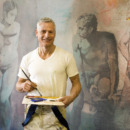 Mature artist with brush and pallette in front of painting, portrait
