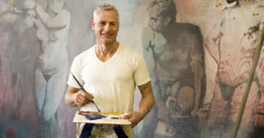 Mature artist with brush and pallette in front of painting, portrait