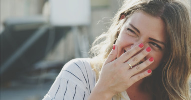 Young Woman Laughing While Hiding Mouth With Hand