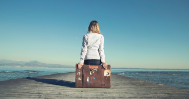 woman sitting on her suitcase waiting for the sunset