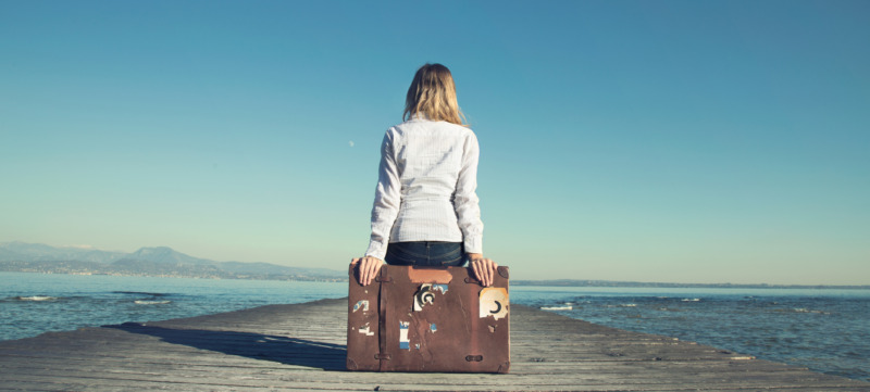 woman sitting on her suitcase waiting for the sunset