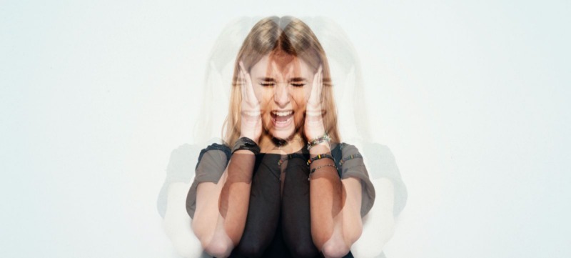 vrouw houdt oren voor haar hoofd ter bescherming van de piep in haar oren