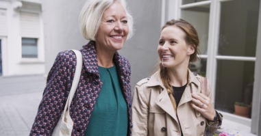 Smiling mother and daughter walking with shopping bags in alley