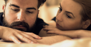 Unhappy young heterosexual couple in bedroom