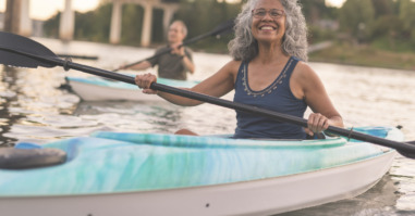 An ethnic senior woman smiles while kayaking with her husband