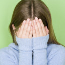 Studio shot portrait of teenage girl covering face, head and shoulders