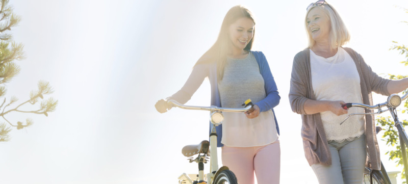 Mother and adult daughter walking bicycles