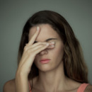 Young woman covering her eyes with one hand