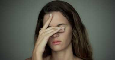 Young woman covering her eyes with one hand