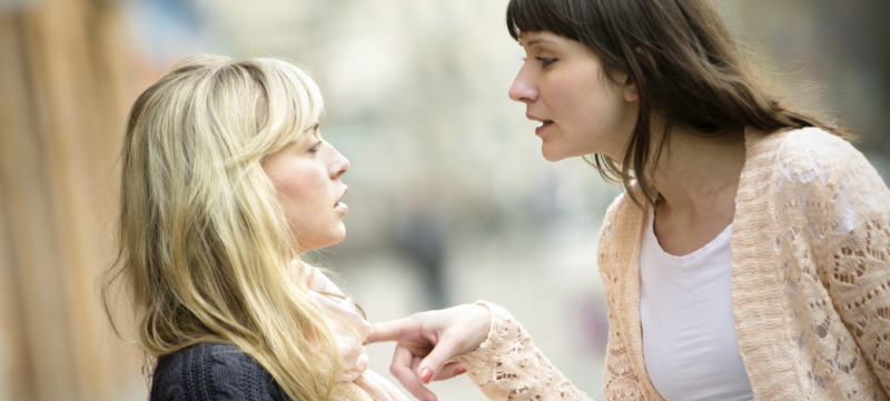 Two women talking to each other and arguing.