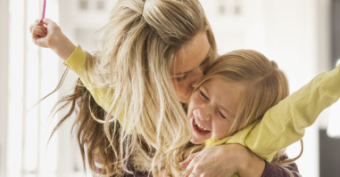 USA, Utah, Lehi, Mother kissing daughter (6-7) during doing homework