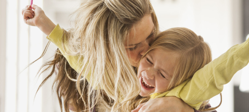 USA, Utah, Lehi, Mother kissing daughter (6-7) during doing homework