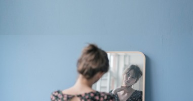 Young woman in vintage dress looking into mirror