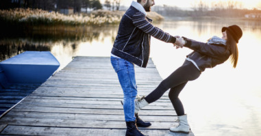 Couple have fun on pier at sunset near the lake