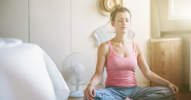 Mid adult woman in yoga lotus position in bedroom
