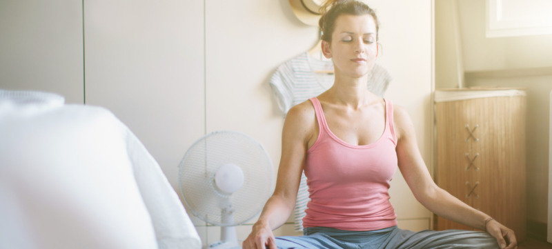 Mid adult woman in yoga lotus position in bedroom