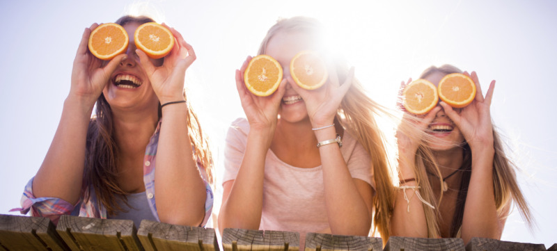 Teen girl friends holding up oranges for eyes