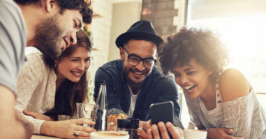 Friends looking at smart phone while sitting in cafe