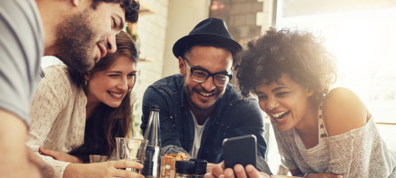 Friends looking at smart phone while sitting in cafe