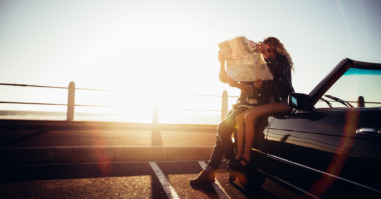 Hipster couple planning their summer seaside road trip with convertible