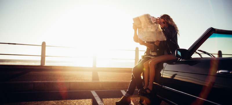 Hipster couple planning their summer seaside road trip with convertible