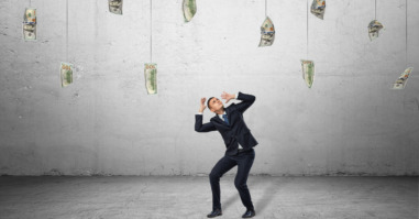 Scared businessman in protective pose with loads of money hanging