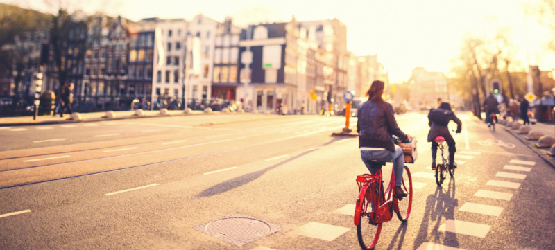 People on bikes in Amsterdam streets at sunset