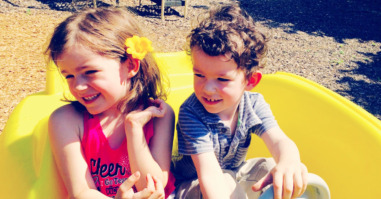 High Angle View Of Siblings In Toy Car At Playground