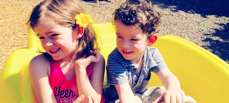 High Angle View Of Siblings In Toy Car At Playground