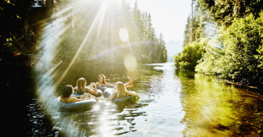 Laughing friends floating on river in inner tubes