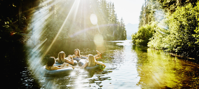 Laughing friends floating on river in inner tubes
