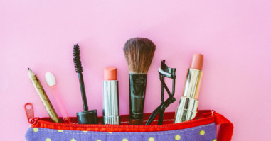 Close-Up Of Beauty Products In Bag Over Pink Background