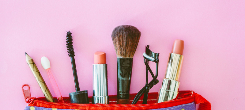 Close-Up Of Beauty Products In Bag Over Pink Background