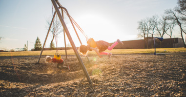 Little kids swinging on swing set on stomach