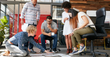 Creative people looking at project plan laid out on floor