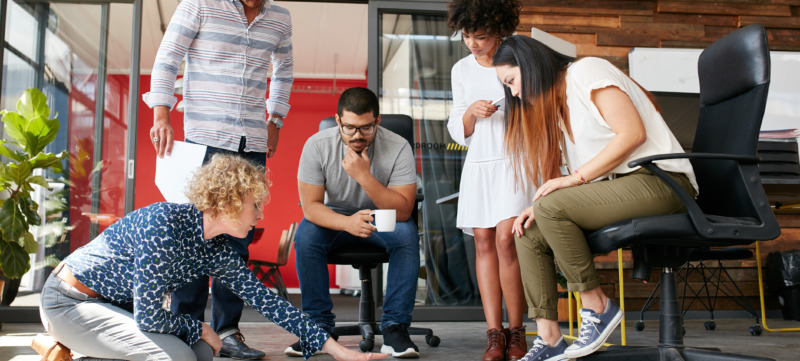 Creative people looking at project plan laid out on floor