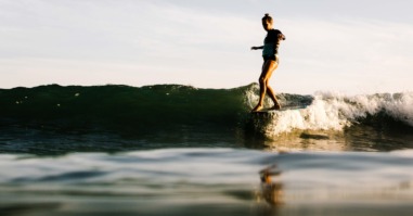 Woman surfing at sunset, Malibu, California, USA