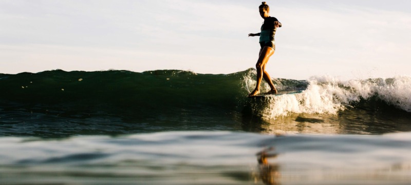 Woman surfing at sunset, Malibu, California, USA