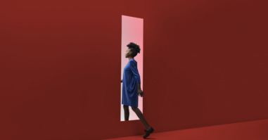 Woman walking threw rectangular opening in coloured wall