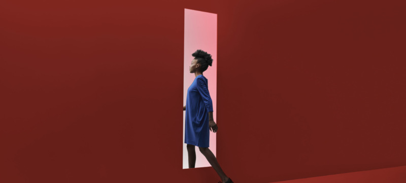 Woman walking threw rectangular opening in coloured wall