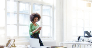 Businesswoman using her phone in open plan office