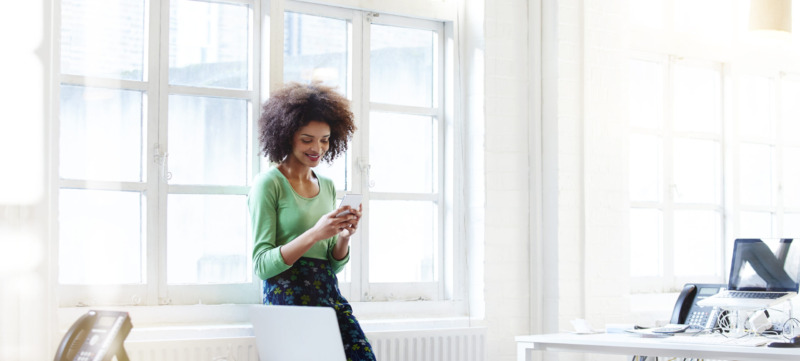 Businesswoman using her phone in open plan office