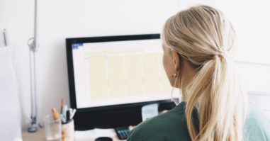 Rear view of female nurse working at computer desk in office