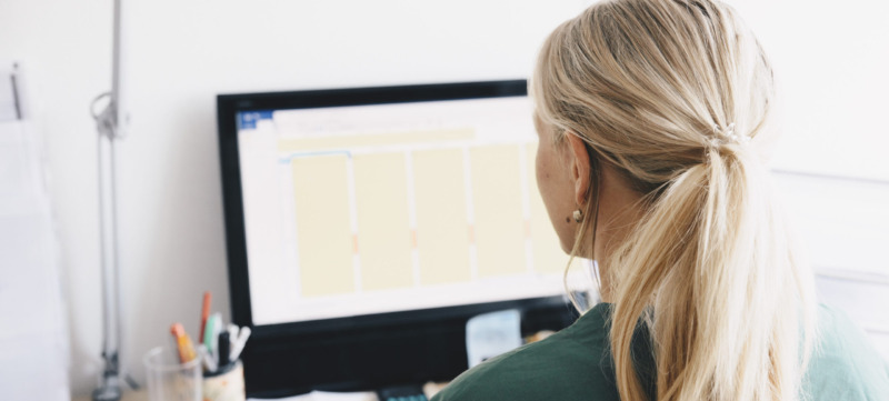 Rear view of female nurse working at computer desk in office
