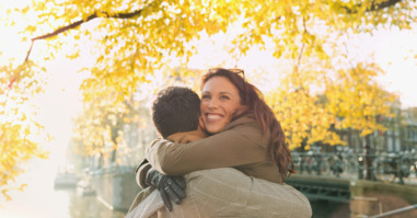 Happy couple hugging along sunny urban autumn canal, Amsterdam