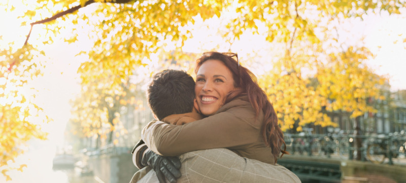 Happy couple hugging along sunny urban autumn canal, Amsterdam