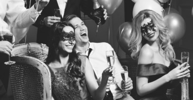Laughing people in masks at party